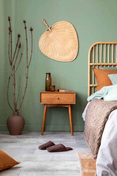 istock Stylish bedroom interior design with mock up poster frame, bamboo bed, night table, plants, folding screen and creative home accessories. Eucalyptus wall. Template. Copy space. 1404392983