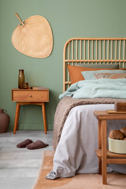 istock Stylish bedroom interior design with mock up poster frame, bamboo bed, night table, plants, folding screen and creative home accessories. Eucalyptus wall. Template. Copy space. 1404392993