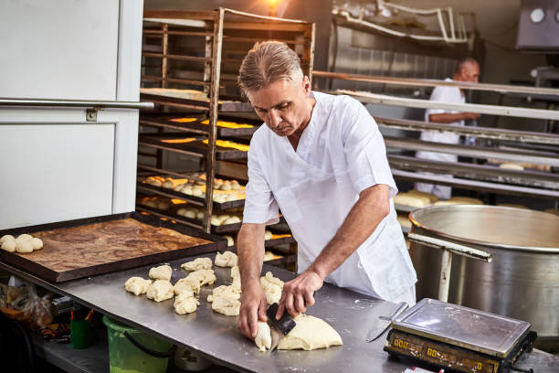 istock Skilled man baker dividing raw dough into equal portions and weights them. Process of making bread in bakery 1404394165