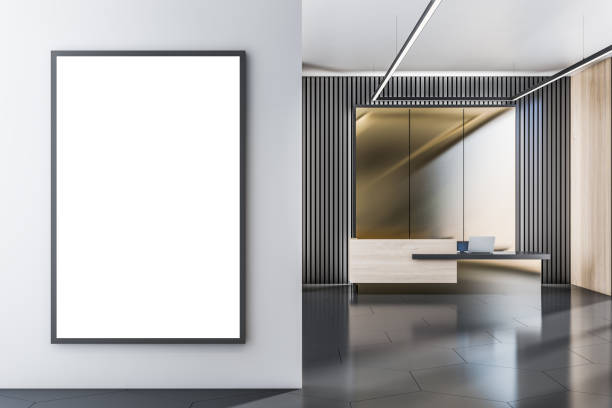 istock Front view on blank white poster with place for your logo or text on light grey wall in sunlit spacious office on modern dark style reception desk background. 3D rendering, mock up 1404396654