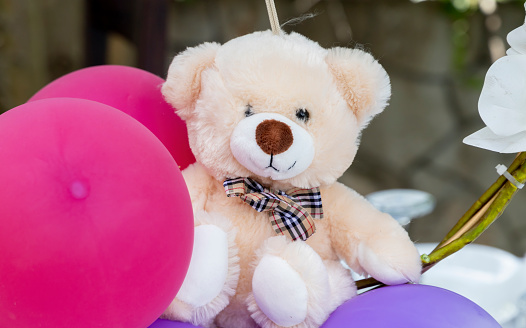 An ornamental teddy bear among balloons