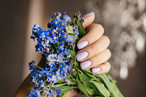 Beautiful purple manicure on a milky background with flowers.