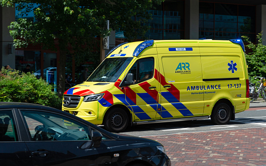 Rotterdam, South Holland, Netherlands, june 17th 2022, yellow Mercedes-Benz 'Sprinter' van ambulance from the Rotterdam-Rijnmond district approaching with emergency lights and siren at the 'Erasmus University Medical Center' downtown Rotterdam - Rotterdam is the second largest Dutch city and globally known for having the largest seaport in Europe, Erasmus MC is  the largest scientific University Medical Center in Europe