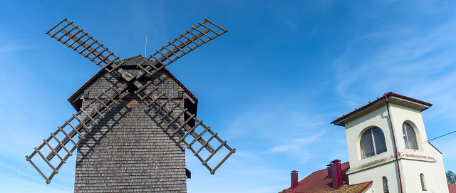 Vintage wooden windmill with cycling track on blue sky background. Historical farm house windmill. Heritage concepts.