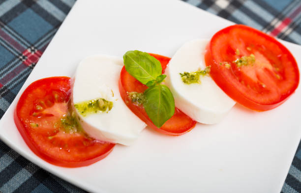 Close up of  Caprese salad. Mozzarella cheese with tomatoes and basil on white plate.Large image for banner.