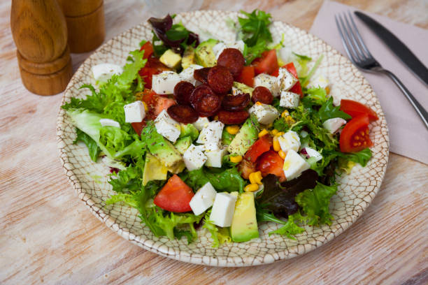Traditional Catalonian food, salad with fried sausages, avocado and cheese on a ceramic plate