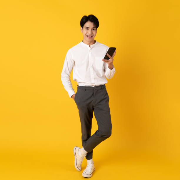 istock Young good looking asian man using smartphone isolated on yellow background 1404400009