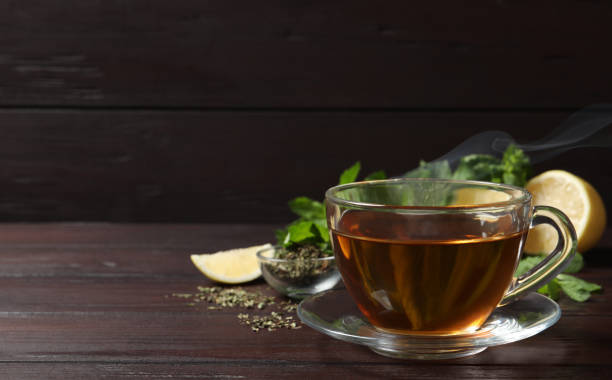 istock Glass cup of freshly brewed tea on wooden table. Space for text 1404401232