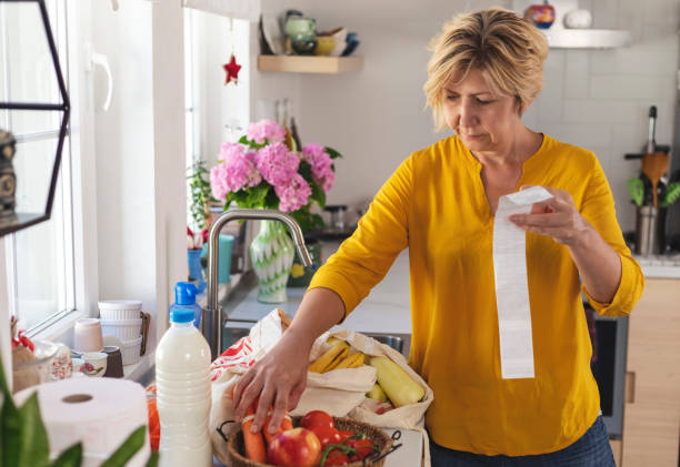 Mature woman going through her receipts at home after buying groceries stock photo
