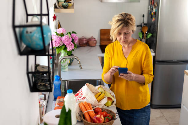 Mature woman going through her shopping list at home after buying groceries stock photo