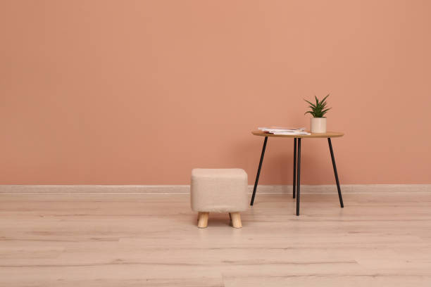 istock Comfortable ottoman and table near pale pink wall indoors, space for text 1404408840