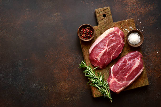 istock Raw organic beef steaks on a wooden cutting board. Top view with copy space. 1404411691