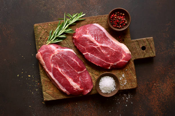 istock Raw organic beef steaks on a wooden cutting board. Top view with copy space. 1404411789
