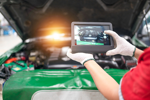 Professional mechanic and check car engine with computer diagnostic software.Expertise mechanic working in automobile repair garage.