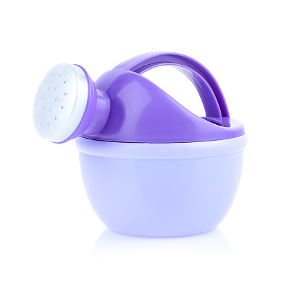 Children's plastic watering can for playing in the sandbox or in the garden. Purple watering can isolated on a white background, close-up.
