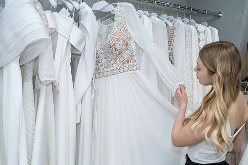 young woman choosing best wedding dress in wedding boutique. Most important wedding day