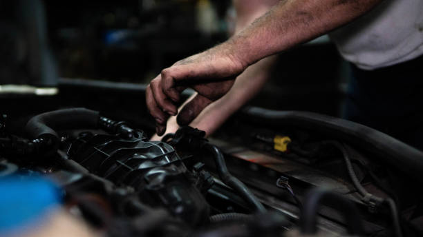 istock Mechanic examining broken car engine while using touchpad in auto repair shop. stock photo 1404417329