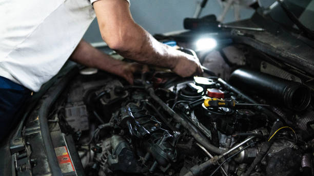 istock Mechanic using flashlight while examining car engine in repair shop. stock photo 1404417502