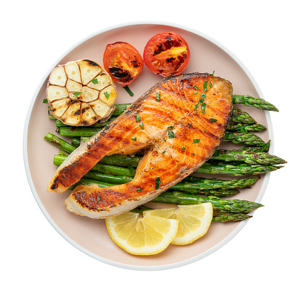 Plate of grilled trout steak and asparagus with ingredients isolated on white background. Top view