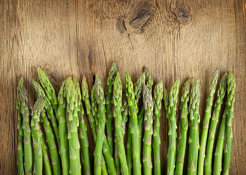 Row of green asparagus on wooden background. Copy space. High quality photo