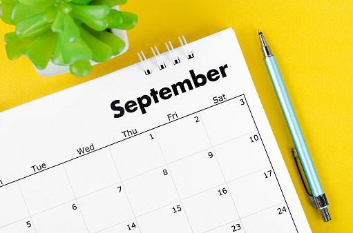 Calendario de escritorio de septiembre de 2022 y bolígrafo con maceta sobre fondo amarillo. photo