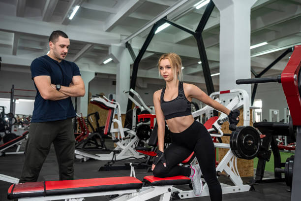 istock male trainer help her woman client working with dumbbell weights at  gym 1404421283