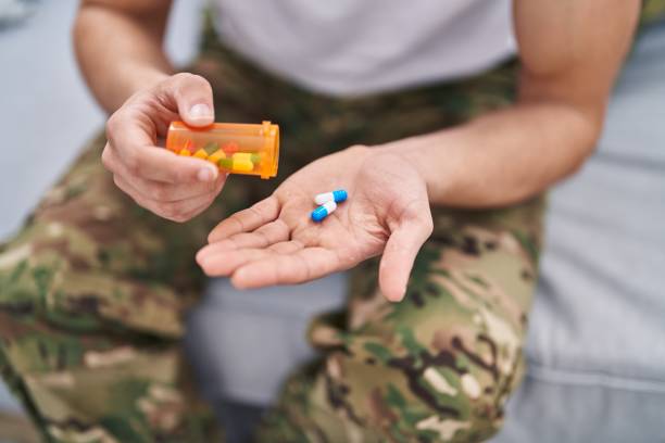 joven soldado del ejército árabe tomando pastillas sentado en el sofá de su casa - personal militar español fotografías e imágenes de stock