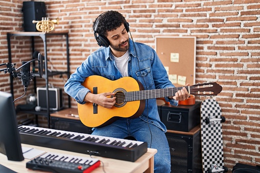Young arab man musician playing classical guitar at music studio
