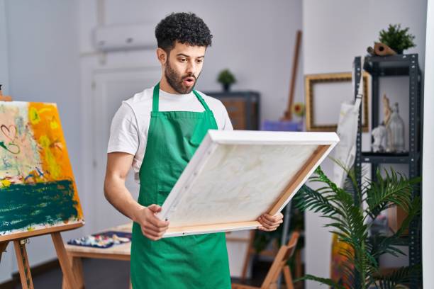 istock Arab man at art studio afraid and shocked with surprise and amazed expression, fear and excited face. 1404422733