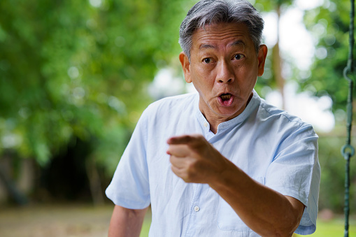 Portrait Of Angry Senior Asian Man Gesturing While Shouting At Outdoor