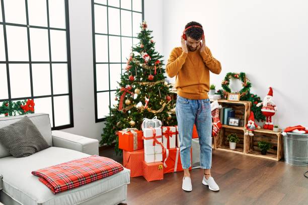 jeune homme arabe écoutant de la musique et dansant debout près du sapin de noël à la maison. - tree house audio photos et images de collection