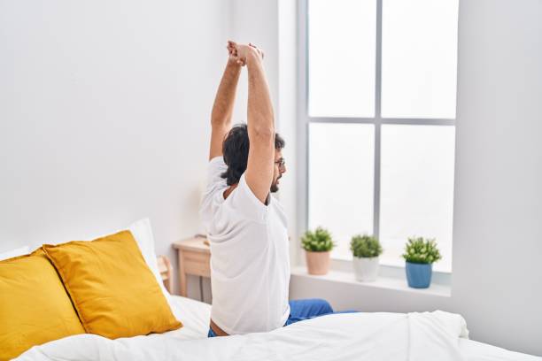 istock Young hispanic man waking up sitting on bed at bedroom 1404423334