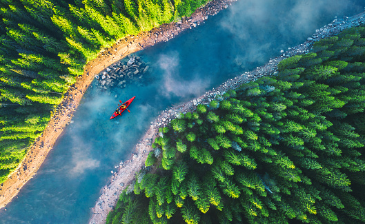 Aerial view of rafting boat or canoe in mountain river and forest. Recreation and camping