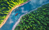 Aerial view of rafting boat or canoe in mountain river and forest. Recreation and camping