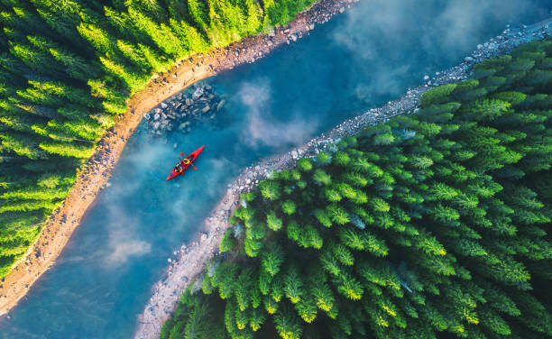 Aerial view of rafting boat or canoe in mountain river and forest. Recreation and camping stock photo