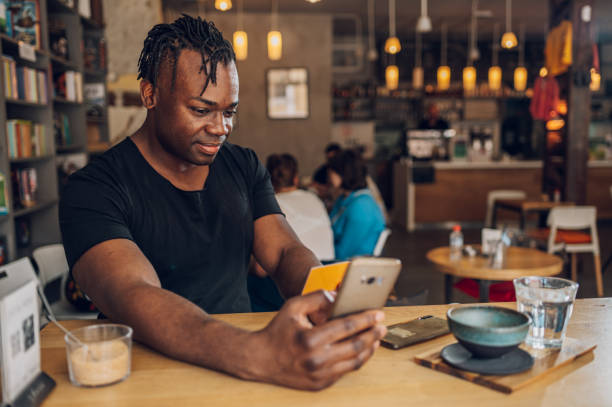 istock African american man using smartphone and credit card in a cafe 1404425894