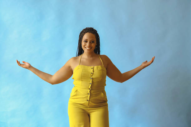 ritratto di grato felice giovane adulto bella donna afroamericana con i capelli a treccia in posa in studio con le mani aperte - arms outstretched foto e immagini stock