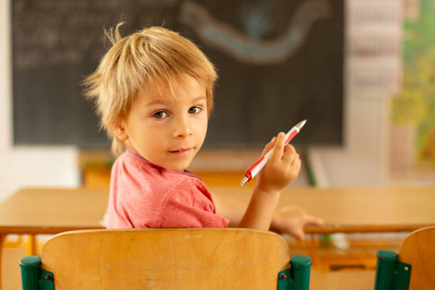Preschool child, sitting on a desk at school, having lesson, learning new things