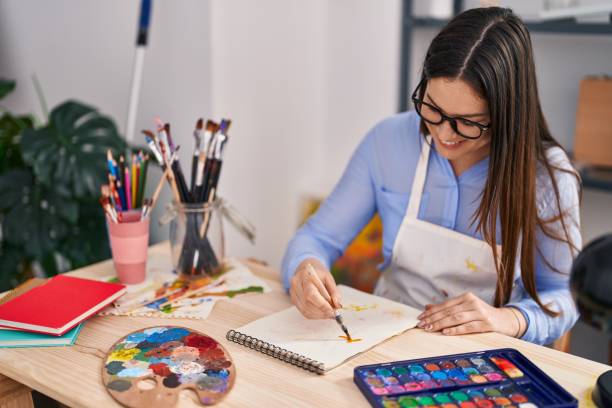 istock Young woman artist smiling confident drawing on notebook at art studio 1404433157