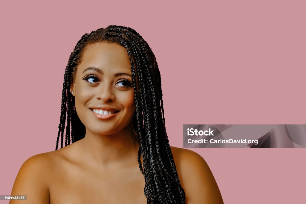 beauty headshot of smiling young adult black woman braid hair on pink background looking away at copy space beauty headshot of smiling young adult black woman braid hair on pink background looking away at copy space studio shot Braided Hair Stock Photo