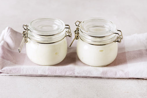 Two Portions of Fresh Natural Homemade Organic Yogurt in a Glass Jar Spoon Gray Background