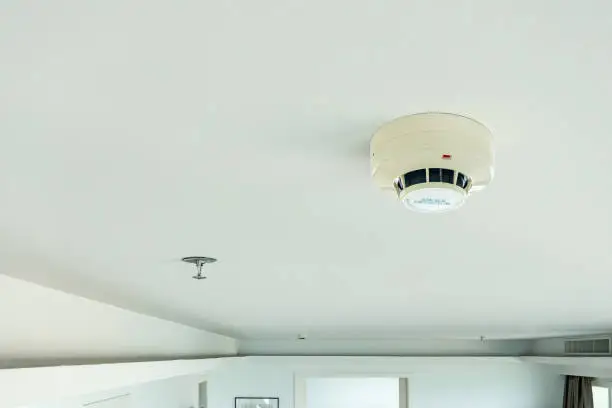 Photo of smoke detector and fire sprinkler on ceiling, fire alarming system and security system at home property for safety domestic life