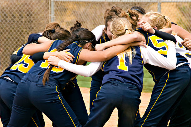 Team Huddle Fastpitch Softball team huddle before the start of a softball game.  Photo is in color.  All logos have been removed. team sport photos stock pictures, royalty-free photos & images