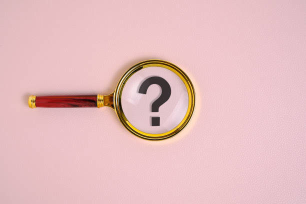 istock Question mark under magnifying glass, on pink background. 1404439298