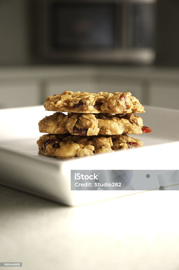 Cranberry White Chocolate Pecan Oatmeal Cookies 3 Cranberry White Chocolate Pecan Oatmeal Cookies stacked on a white square plate with shallow depth of field. Cookie Stock Photo