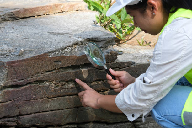 Asian female geologist researcher analyzing rocks with a magnifying glass in a natural park. Exploration Geologist in the Field. Stone and ecology concept. Asian female geologist researcher analyzing rocks with a magnifying glass in a natural park. Exploration Geologist in the Field. Stone and ecology concept. geologist stock pictures, royalty-free photos & images