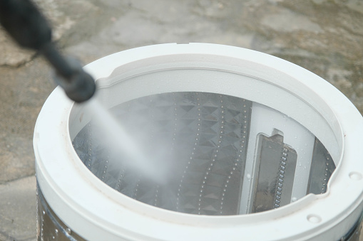 Close-up of washing machine drum descaling with high-pressure cleaner. Parts and accessories inside of machine for washing clothes that have been removed to clean and remove dirtdescale.
