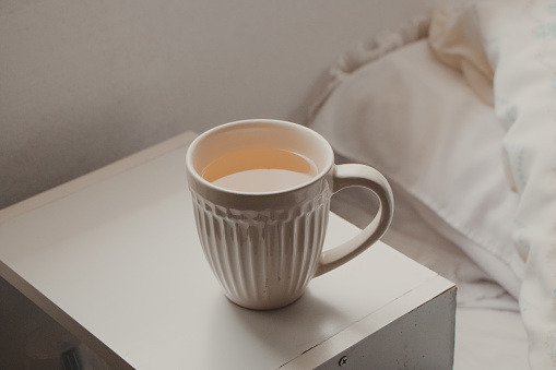 simple white mug with tea next to bed