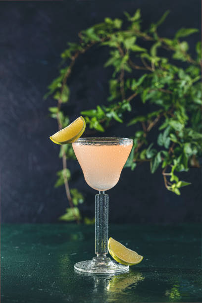 Glass of refreshing Pegu Club cocktail served on dark green table surface stock photo
