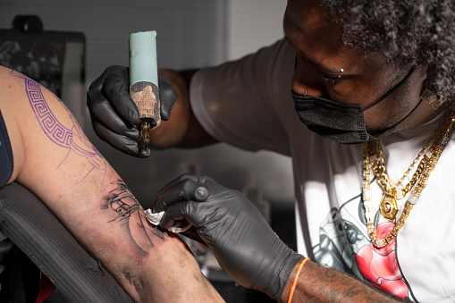 Cinematic shot of a Tattoo artist creating Body art at the tattoo studio. High quality photography